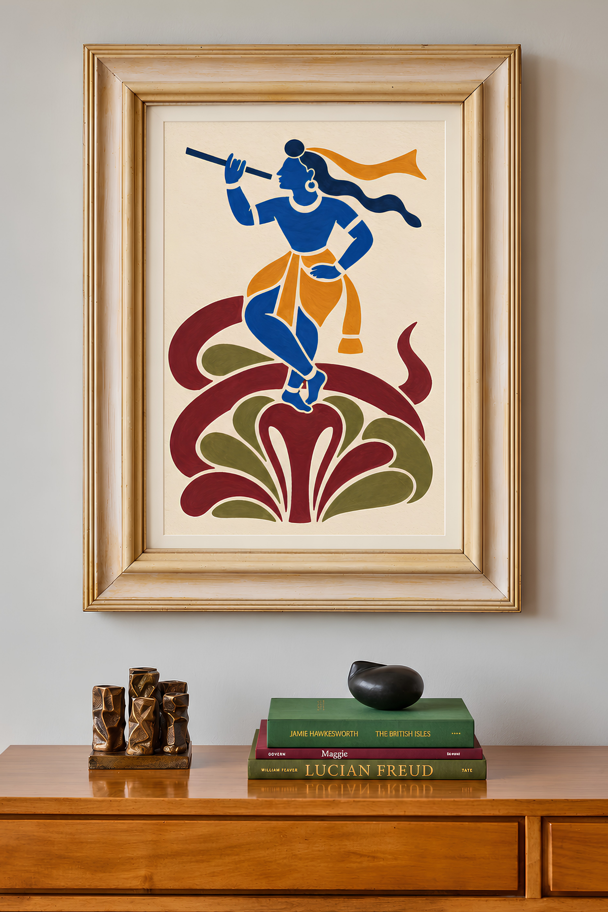 Framed Krishna-on-serpent painting on a wall above a wooden sideboard with books and small sculptures