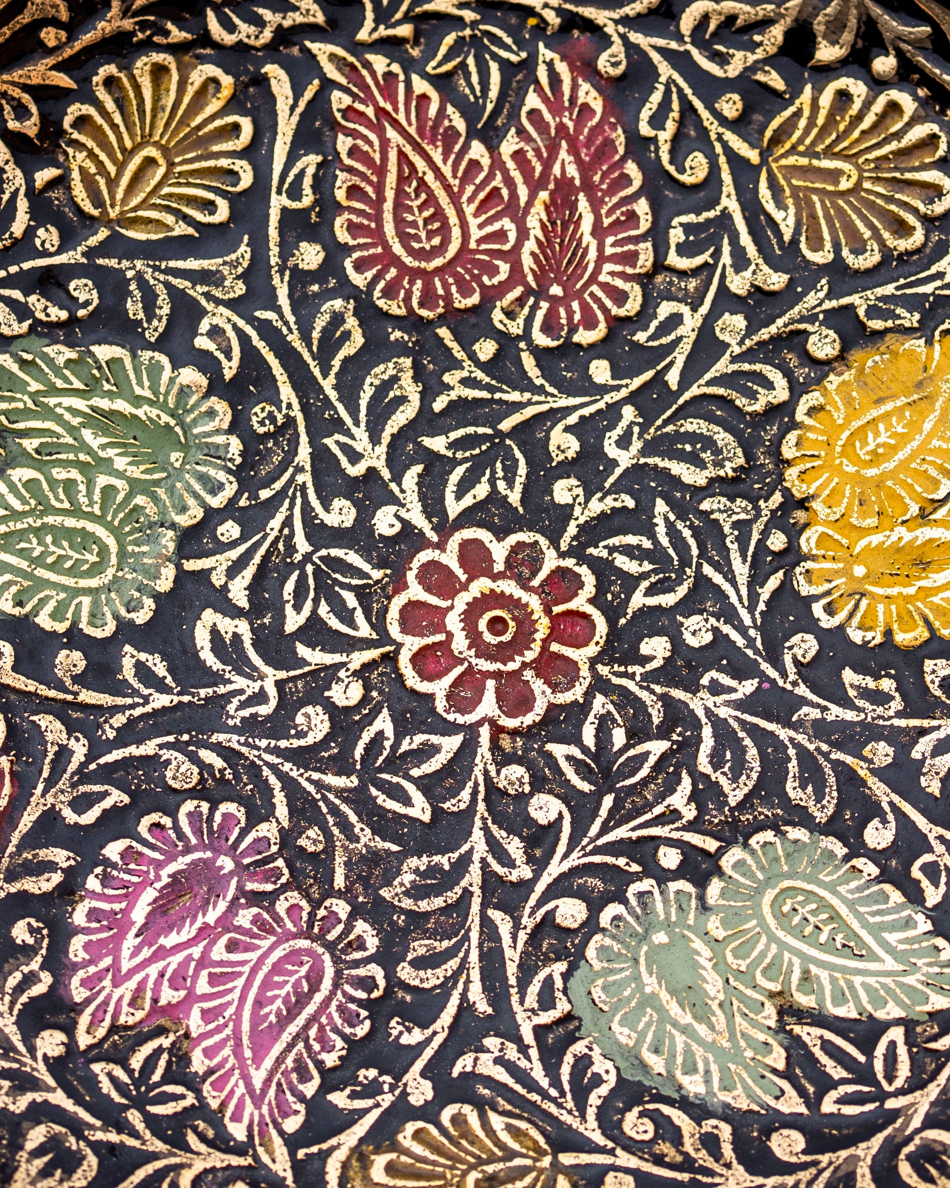 Close-up of hand-painted floral detailing on ornate brass bowl – traditional Indian artisan decor accent.