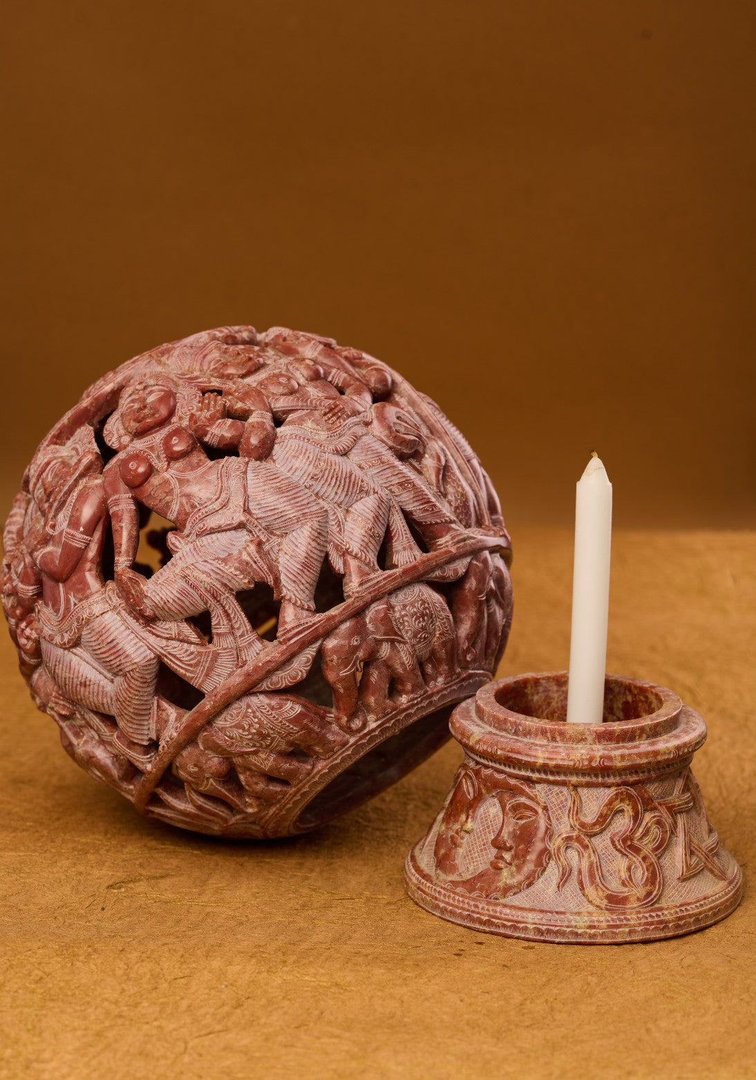 Red stone carved lamp with candle beside it – warm Indian spiritual décor accent.