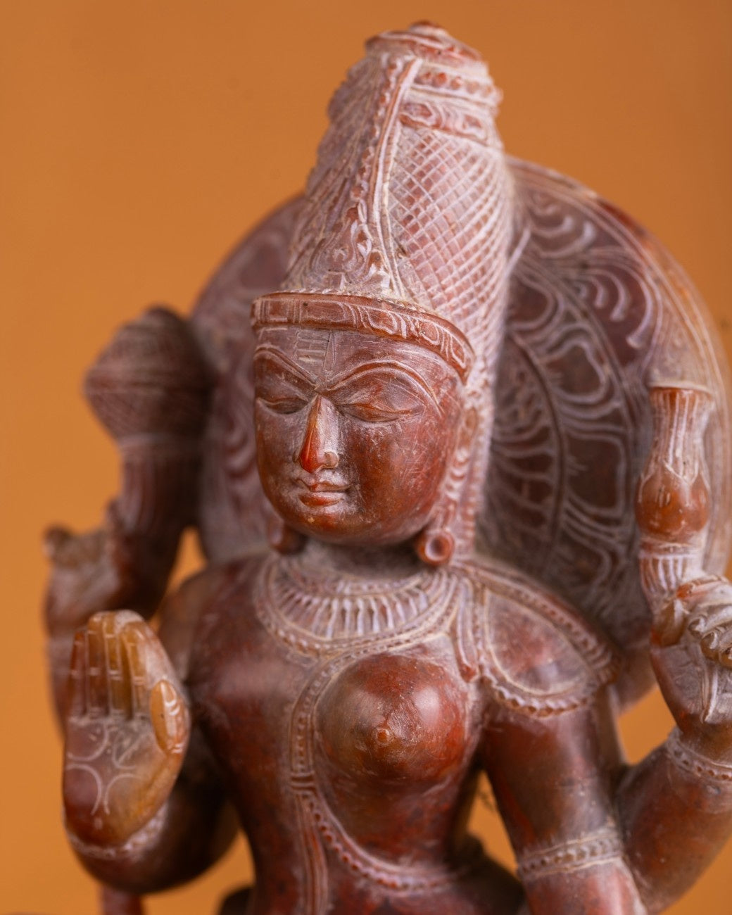 Red stone Ardhanarishwar sculpture displayed in home décor setting, Indian sacred art.