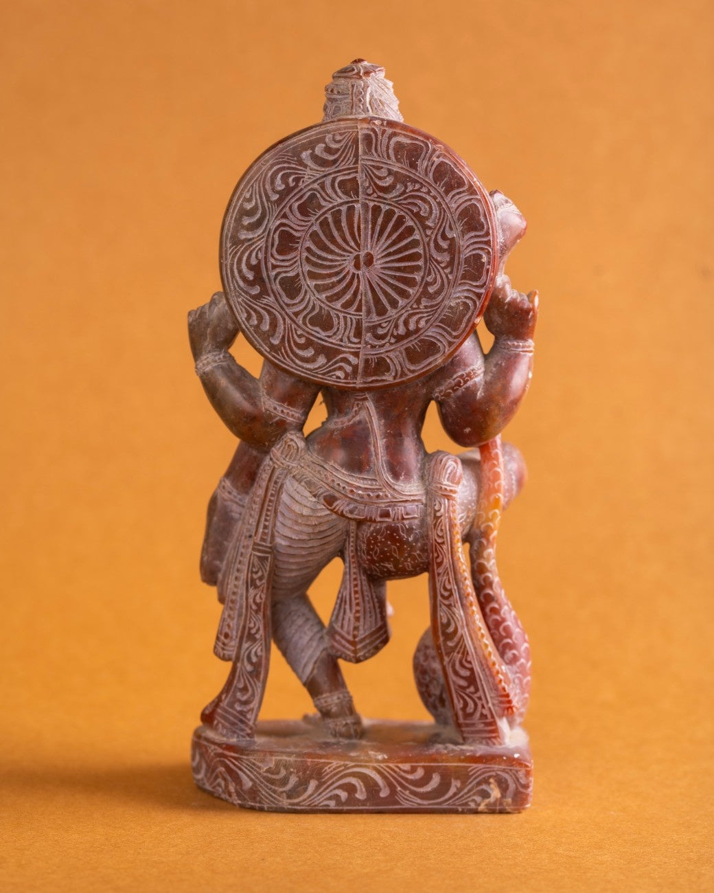 Back details of red stone Ardhanarishwar sculpture highlighting traditional Indian craftsmanship.