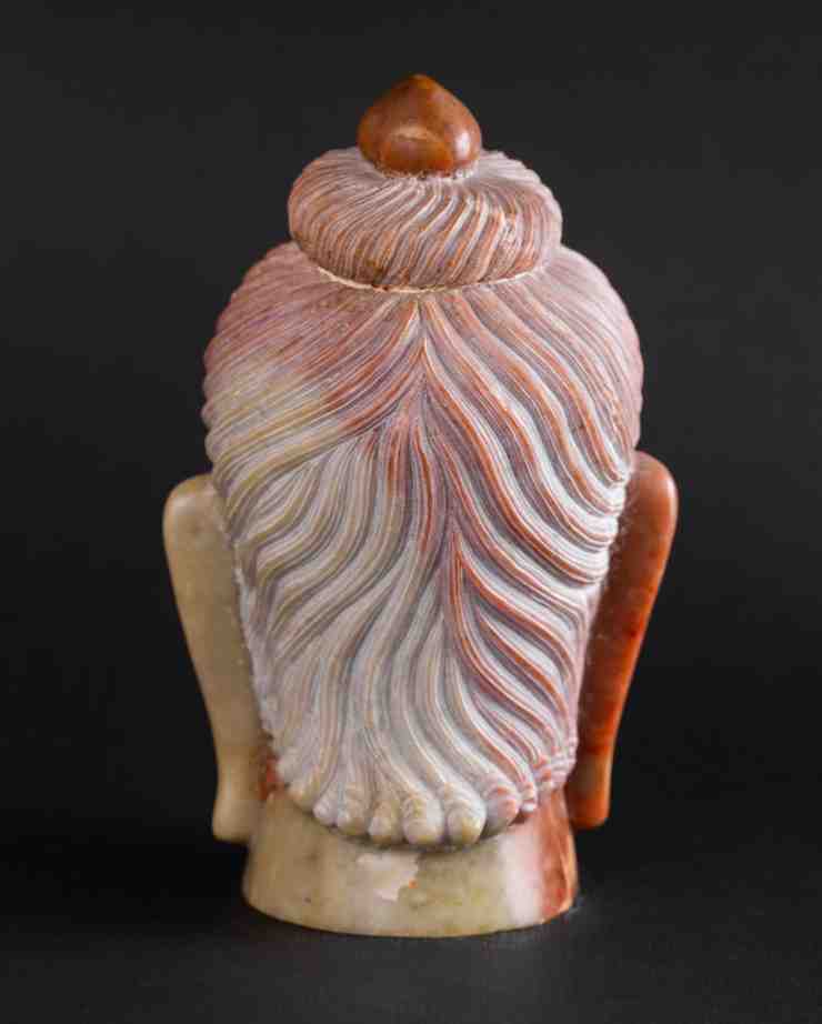 Back view red stone Buddha head sculpture highlighting natural stone texture and variegation