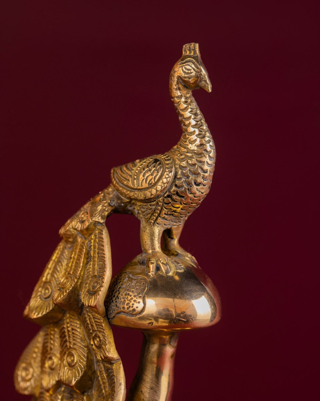 Decorative brass peacock on a red background