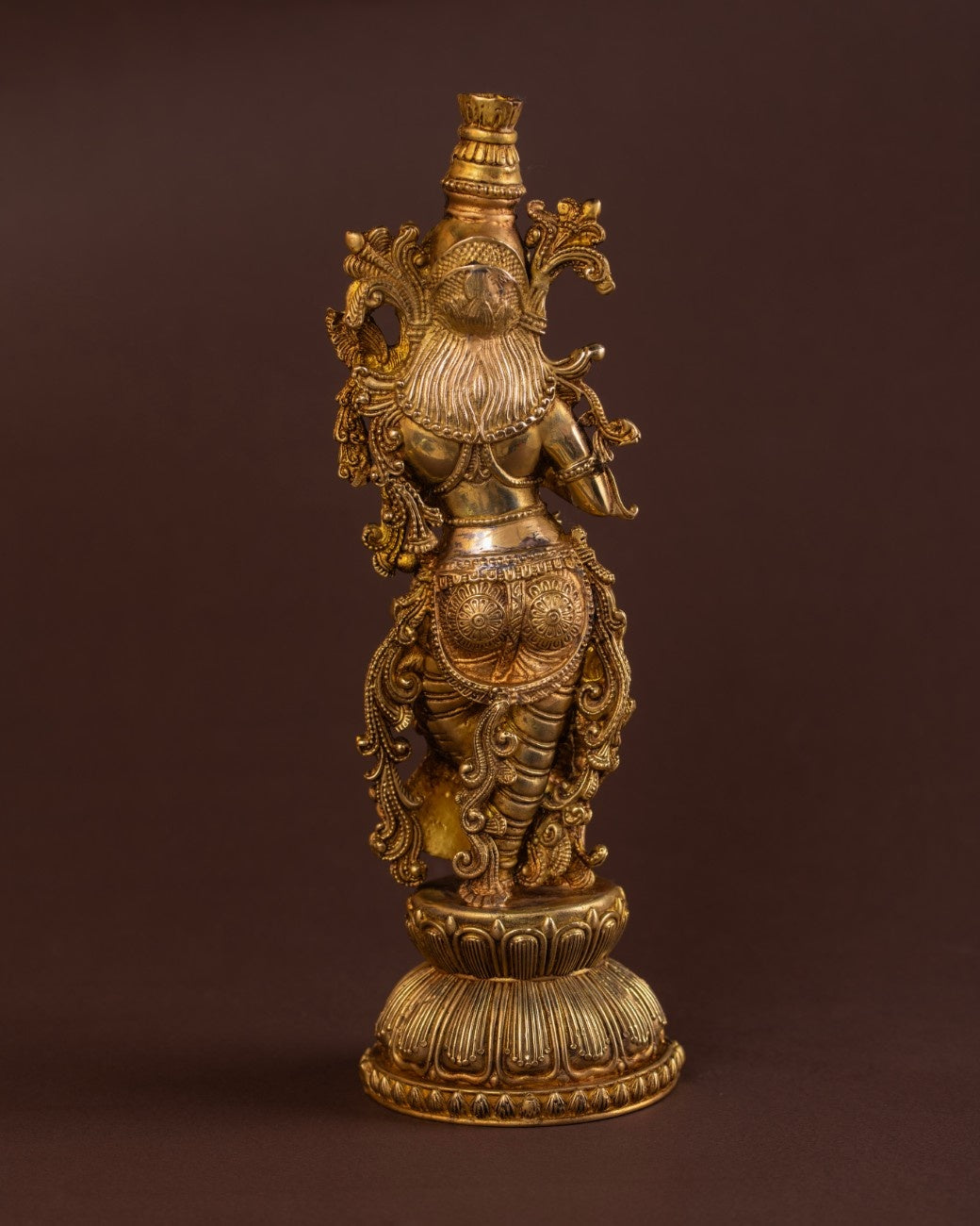 Rear view of brass Radha figurine showcasing carved drapery, detailed ornaments, and Indian devotional craftsmanship