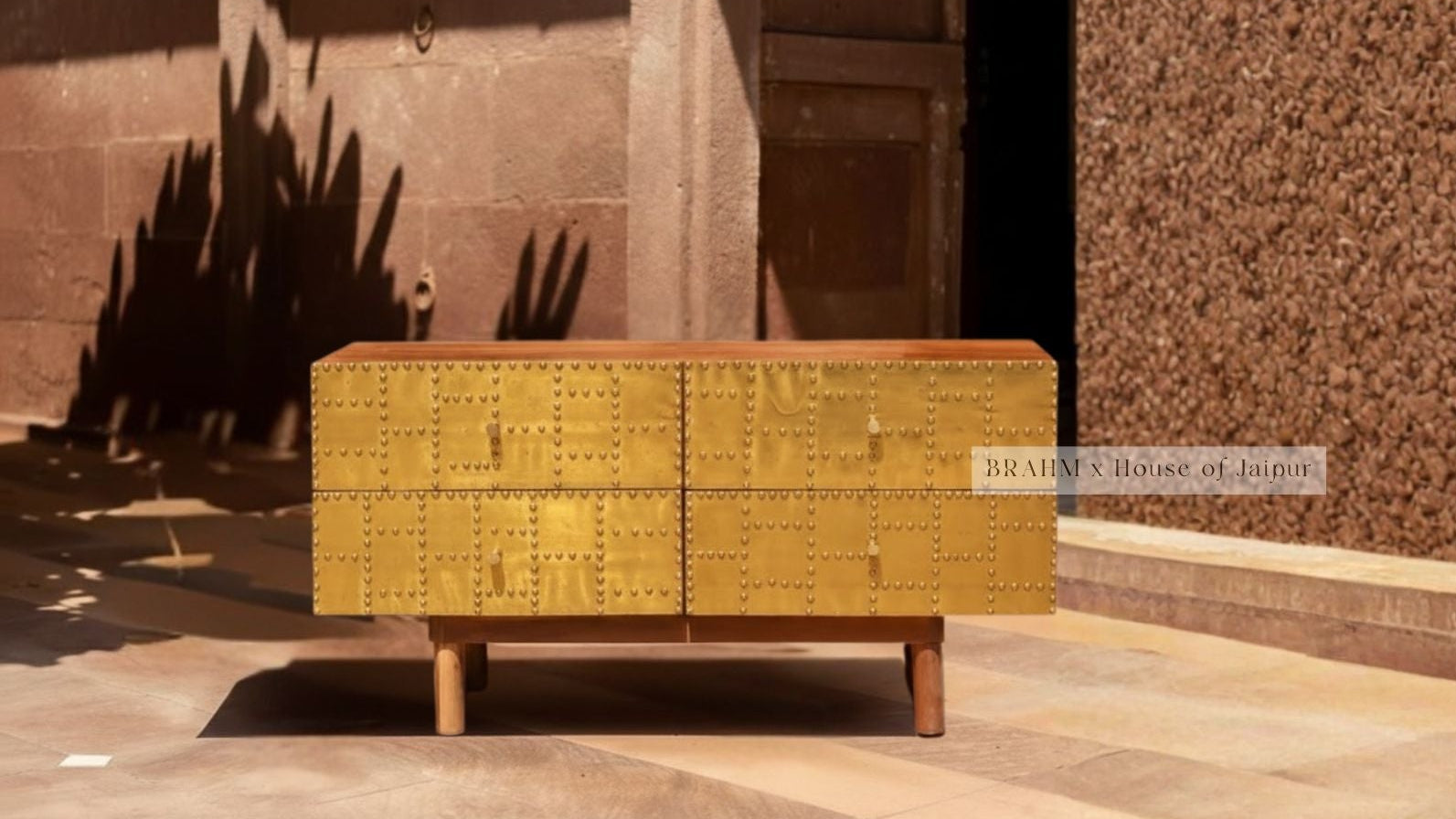 Yellow metallic cabinet with 'house of jaipur' branding against a stone wall.