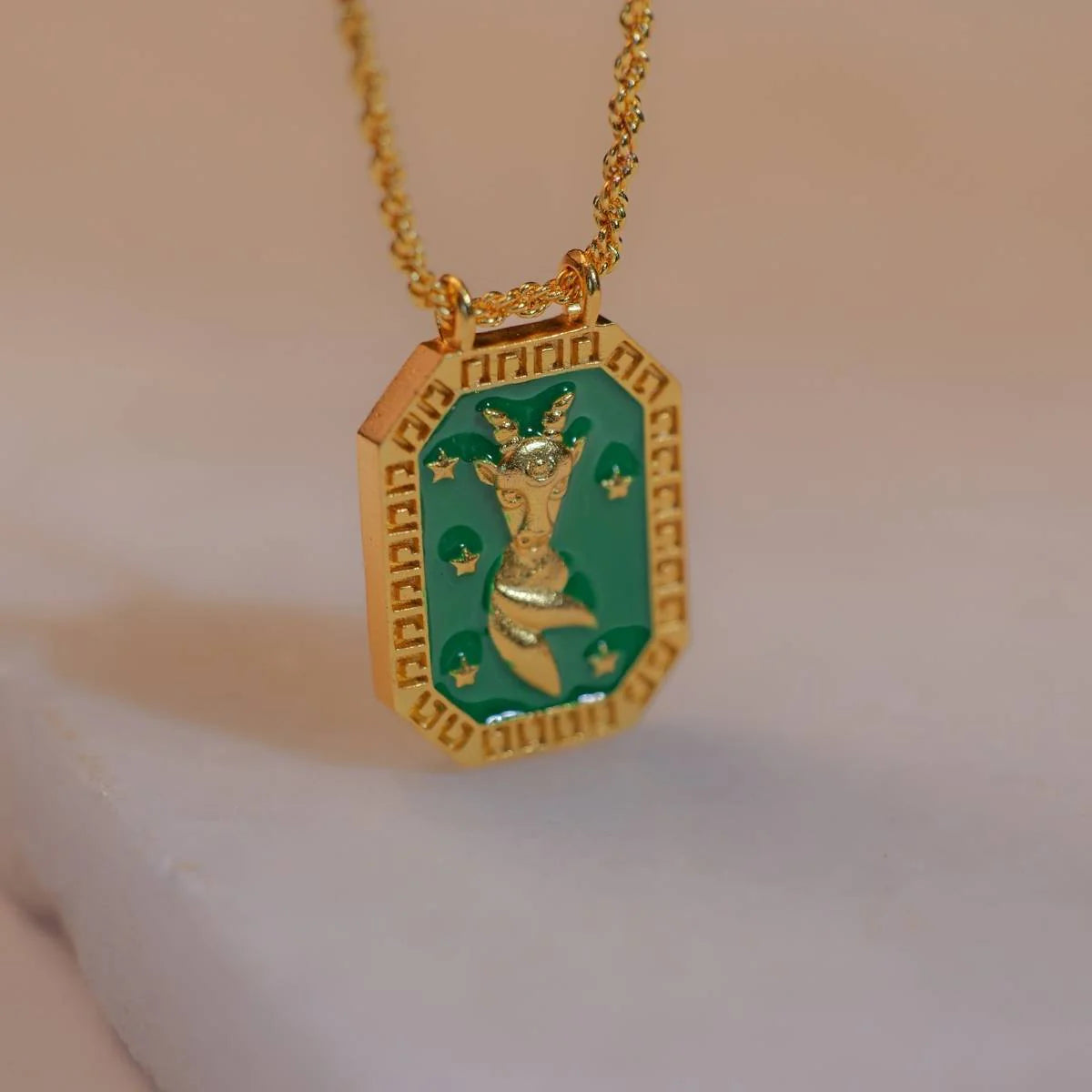 Gold Capricorn zodiac tablet necklace with green enamel front and goat motif