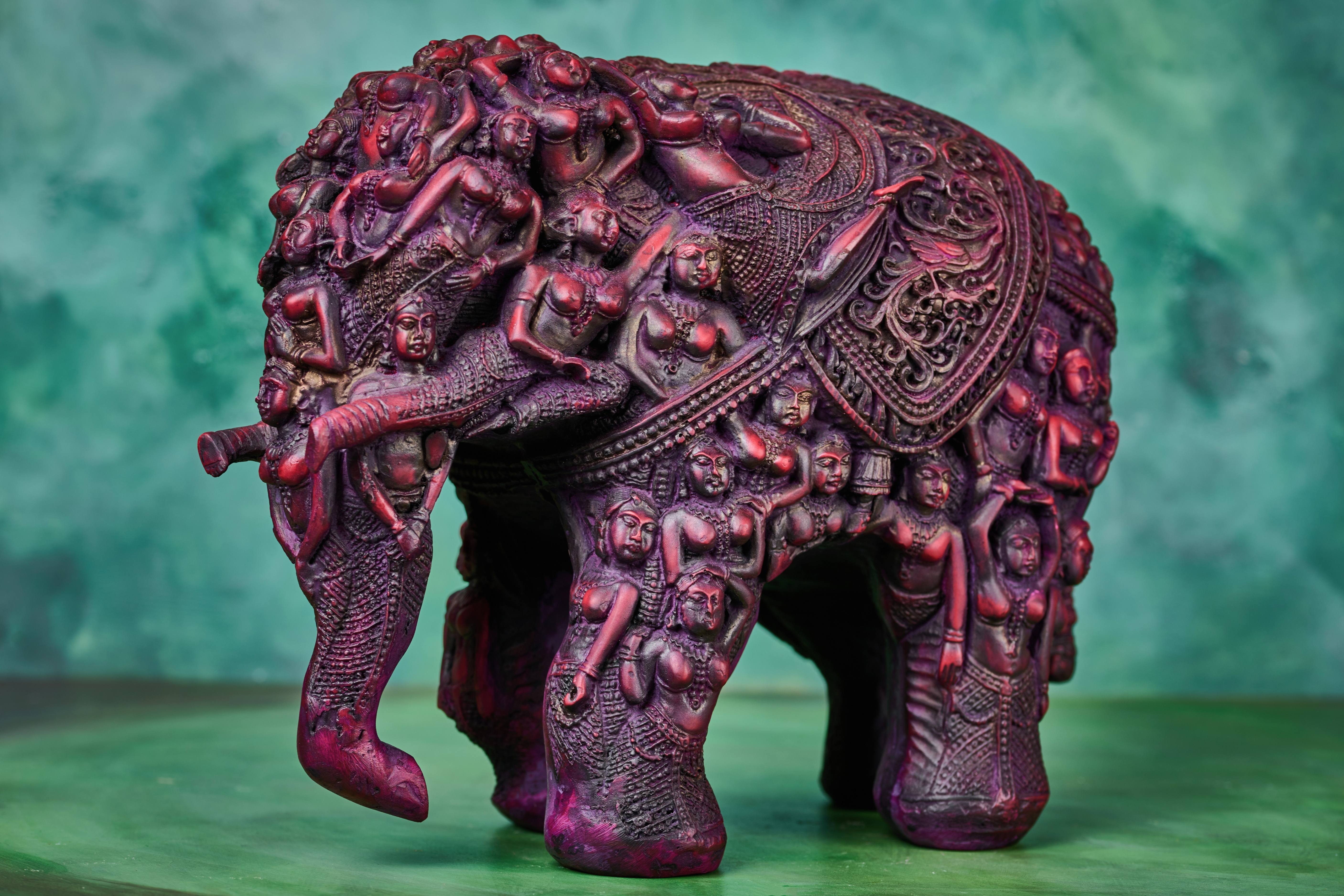 Hand‑carved wooden elephant statue with etched decorative patterns, natural finish