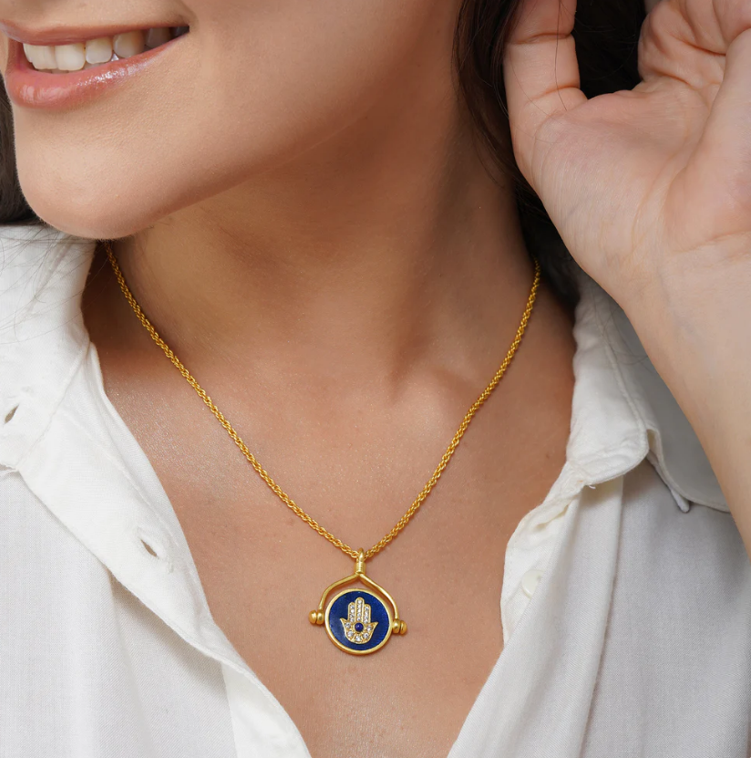 gold-plated evil eye hamsa necklace on decor setup, modern spiritual protection jewelry