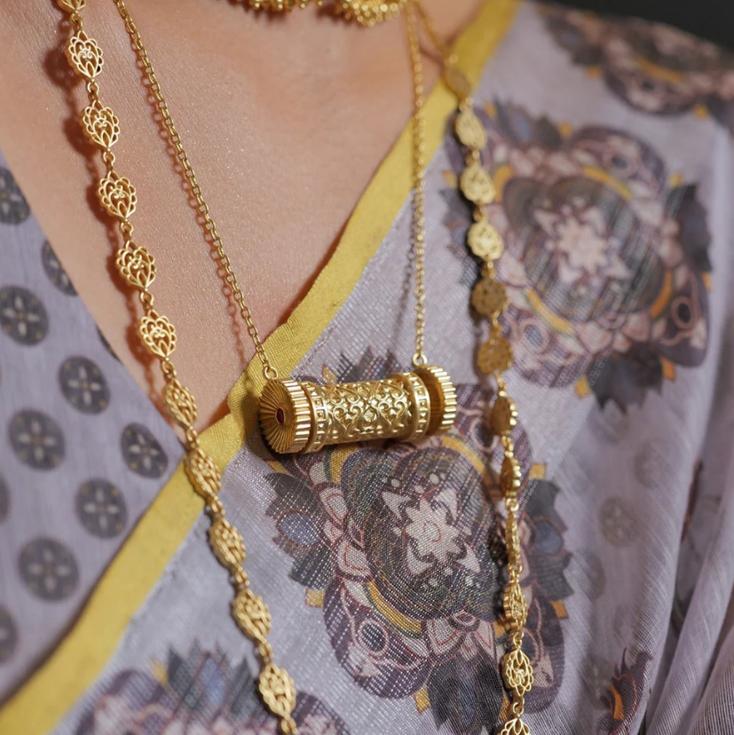 woman wearing gold-plated cylindrical scroll pendant layered necklace, statement gold jewelry for women, perfect for festive styling