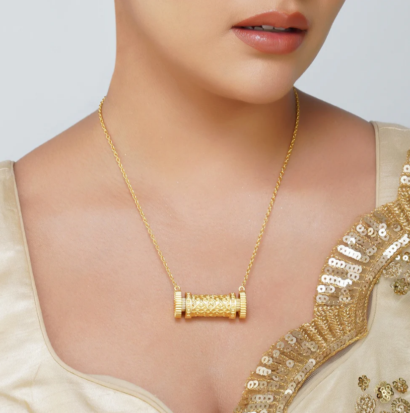 model wearing polished gold-plated cylindrical scroll pendant necklace, minimalist statement jewelry for women, suitable for daily wear and gifting