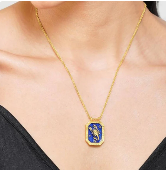 Close-up of gold Scorpio zodiac necklace with blue enamel front and scorpion motif