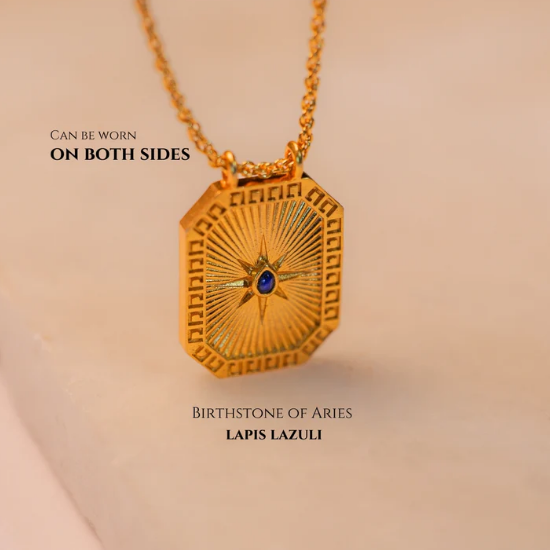 Close-up of gold Virgo pendant with lapis lazuli back shown on soft fabric