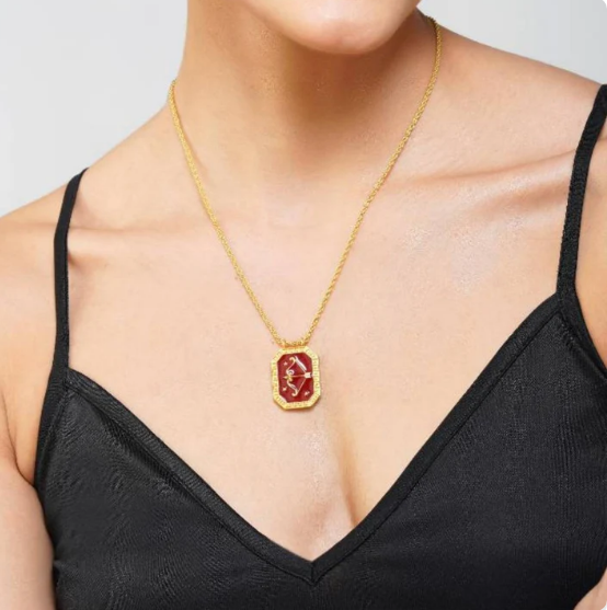 Model wearing gold Sagittarius zodiac tablet necklace with red enamel pendant