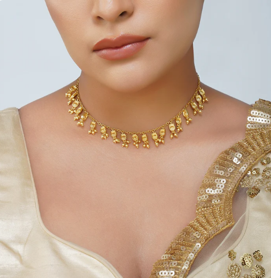Model wearing gold charm necklace styled with saree for an elegant festive look