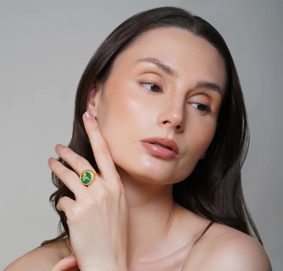Model posing with gold Ma ring featuring round malachite setting