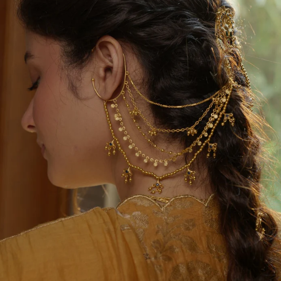 Bride wearing gold chain ear cuff with cascading layers and charm drops styled for traditional look