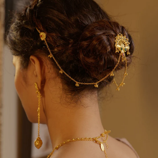 Bride wearing gold peacock juda pin with dangling chains styled on a traditional hair bun