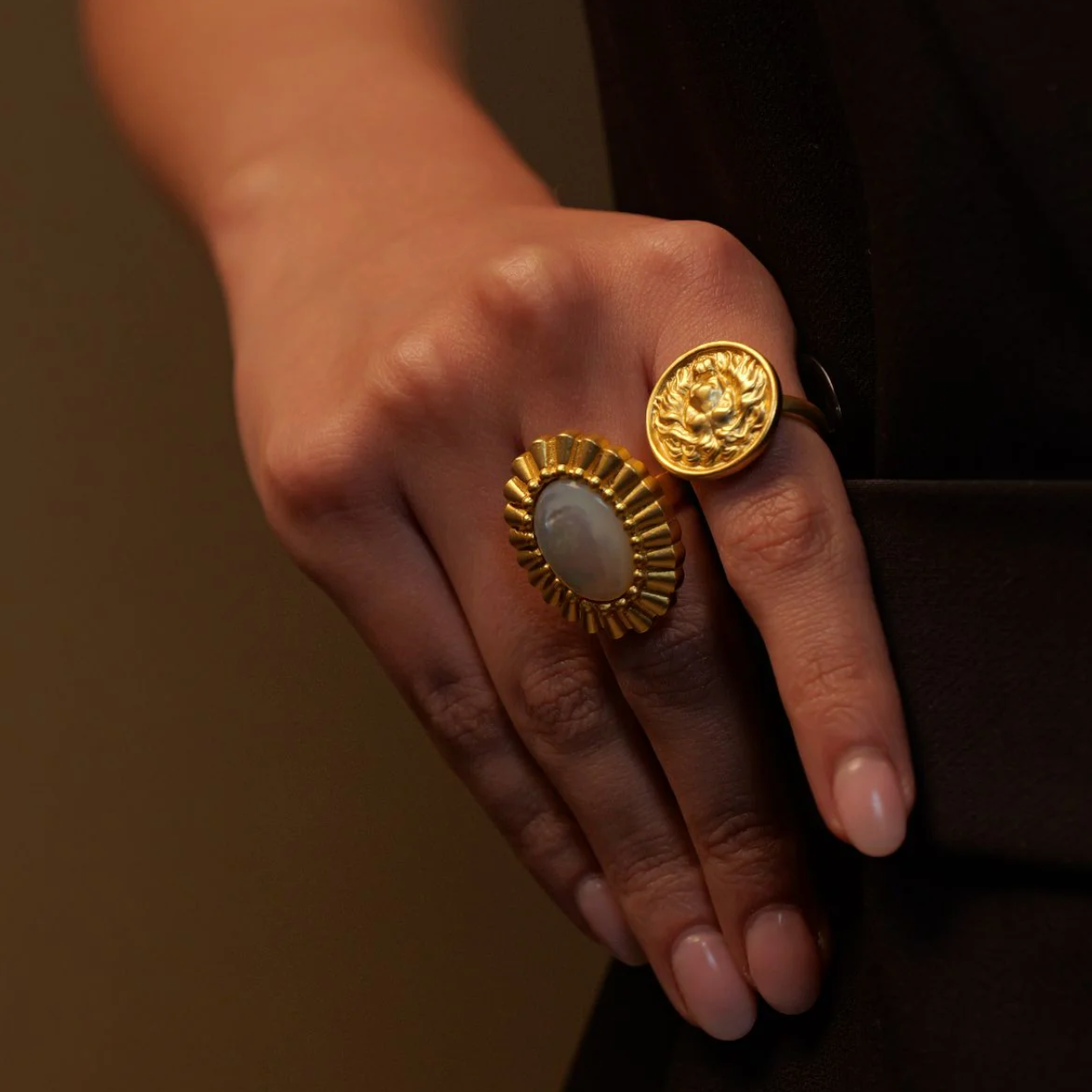 Close-up of hand wearing gold lion head ring with textured medallion