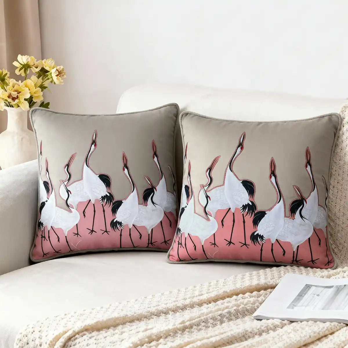 Sedge Pink cushion cover with embroidered cranes on a pink patch, styled on a neutral sofa.