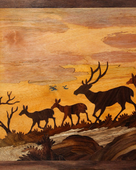Close-up of Mysore rosewood inlay artwork showing detailed deer silhouettes, trees, and layered wood textures created through precision hand-inlay and carving techniques.