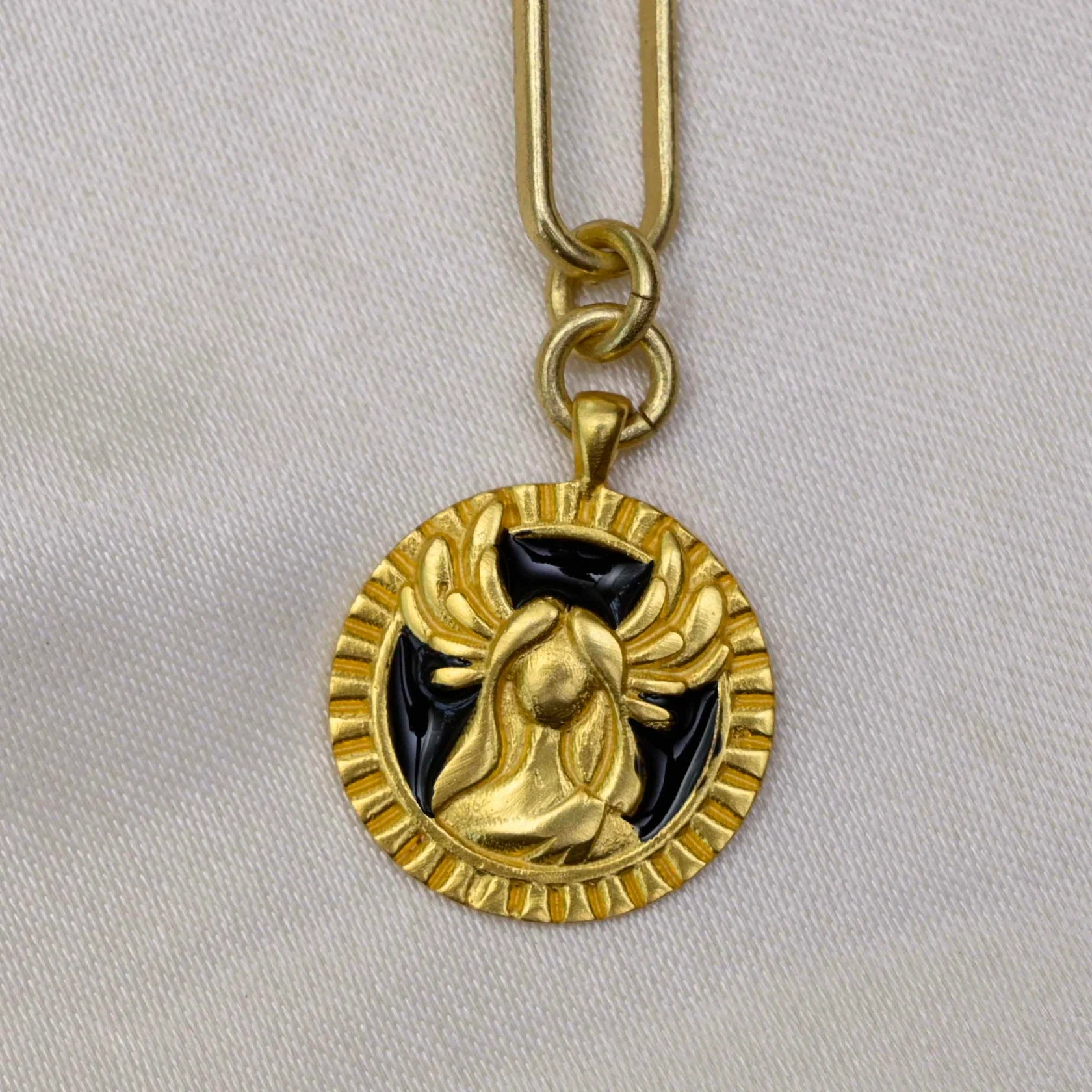 Close-up of gold Virgo medallion pendant with black enamel detailing