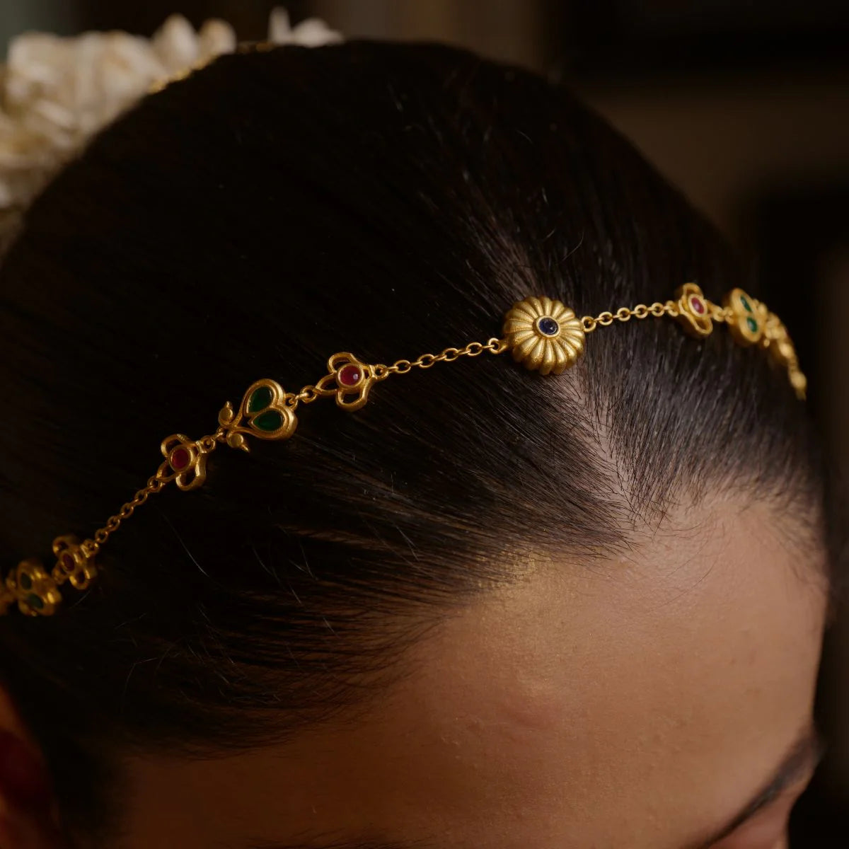 Close-up of matha patti worn on forehead showing gold floral design and gemstone work