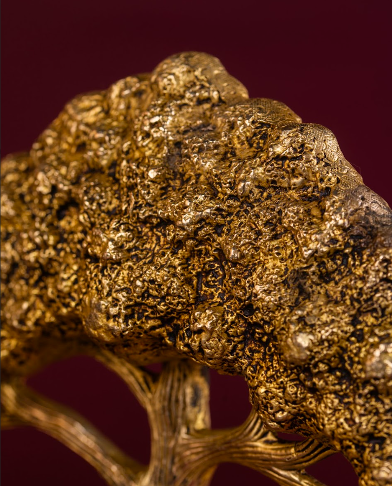 Macro detail of brass Banyan Tree leaves showing clustered foliage and metallic texture