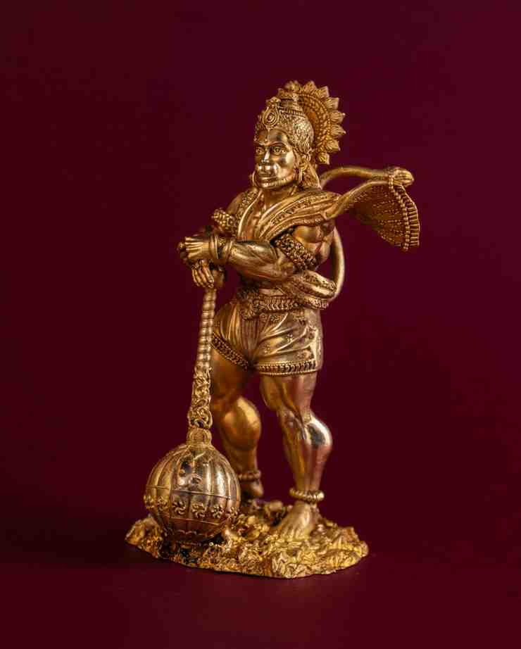 Side profile of brass Hanuman statue carrying traditional gada, detailed Ramayana-inspired Hindu figurine.