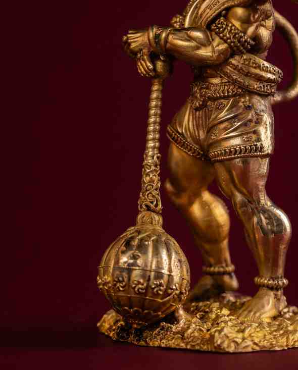 Close-up of brass Hanuman statue showing muscular form, and intricate artisan engraving