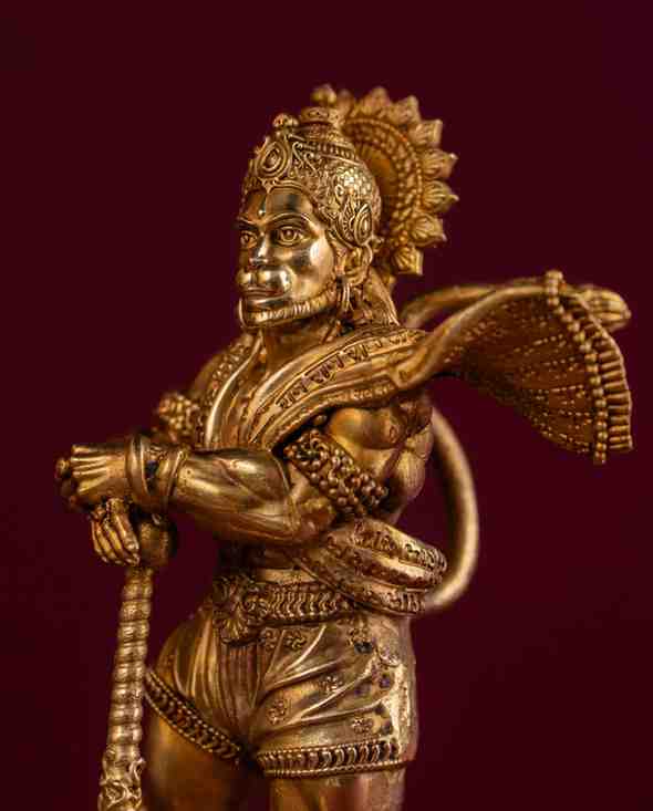 Brass Hanuman sculpture on decorative pedestal with dynamic pose and carved metalwork, devotional Hindu art piece.