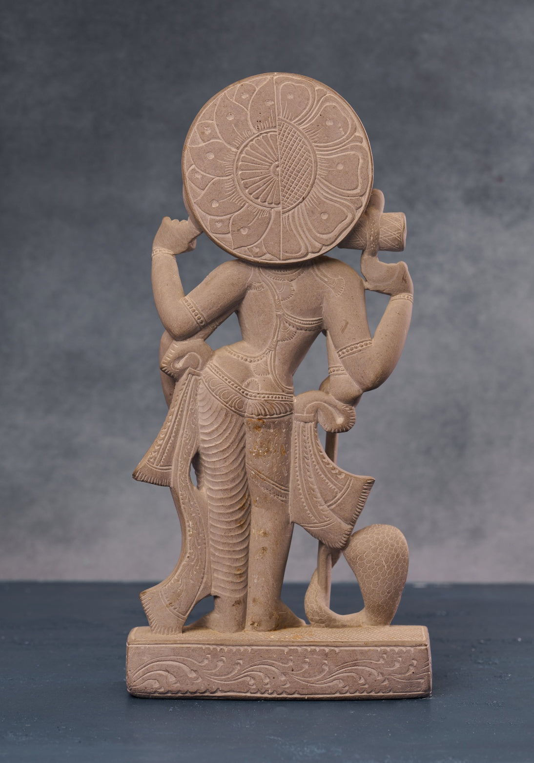 Back view of Ardhanarishvara stone statue showing carved halo and robe detailing, handcrafted Hindu artwork.