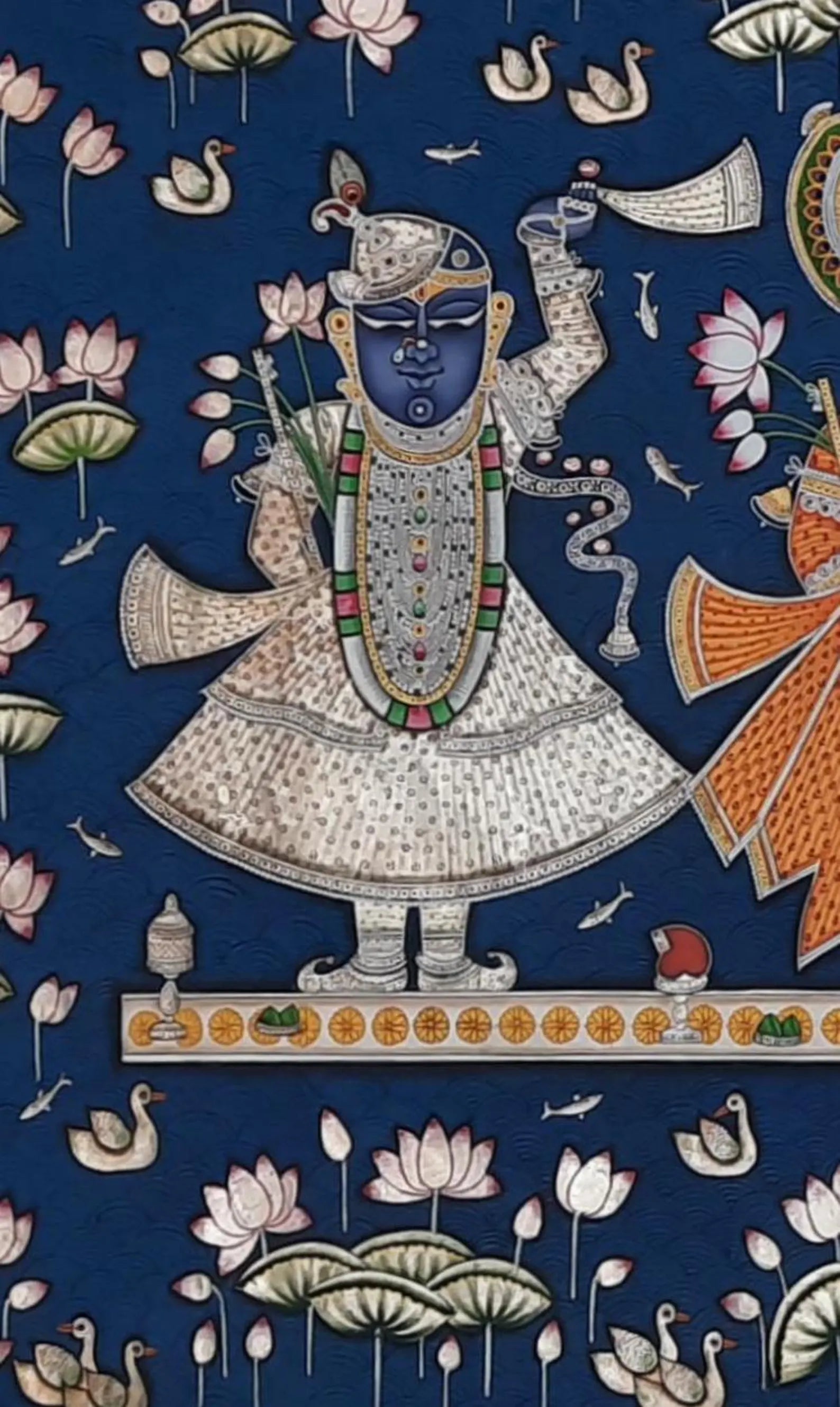 Close-up of Lord Shrinathji figure in Pichwai painting, showcasing ornate attire, lotus motifs, and fine brushwork