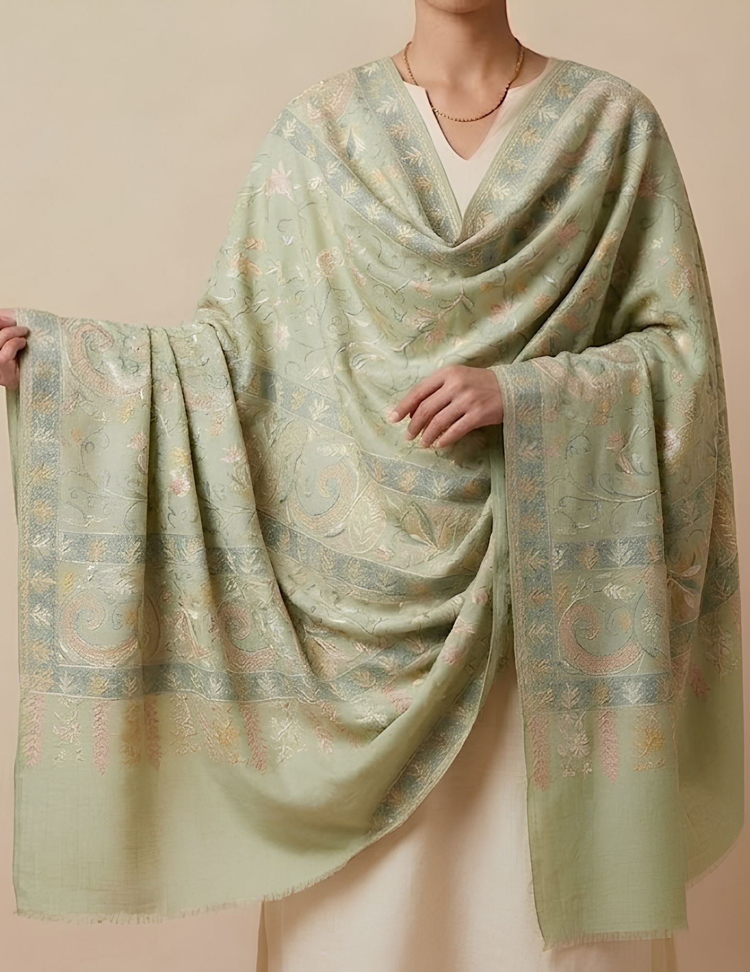 Close-up of Sozni paisley and botanical vine embroidery on sage green wool silk.
