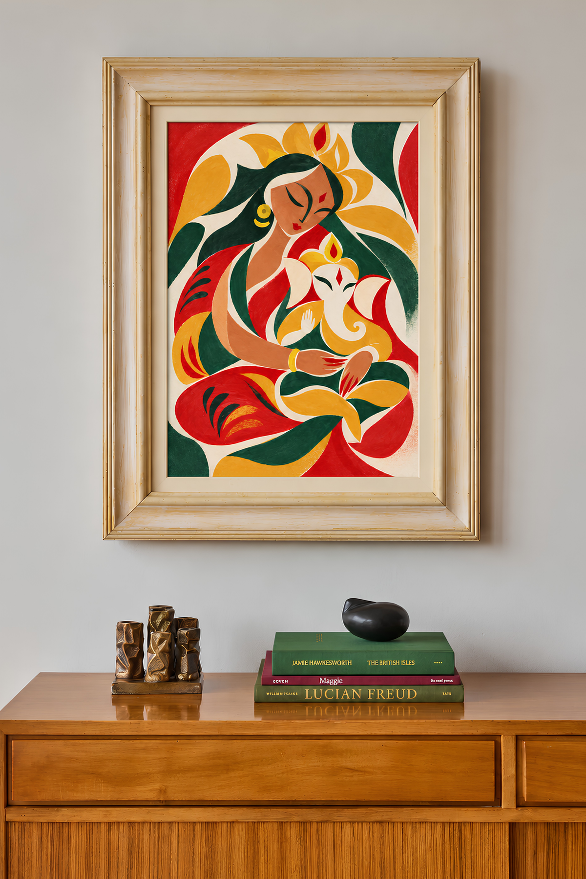 Framed mother-and-Ganesha painting on a wall above a wooden sideboard with books and small sculptures