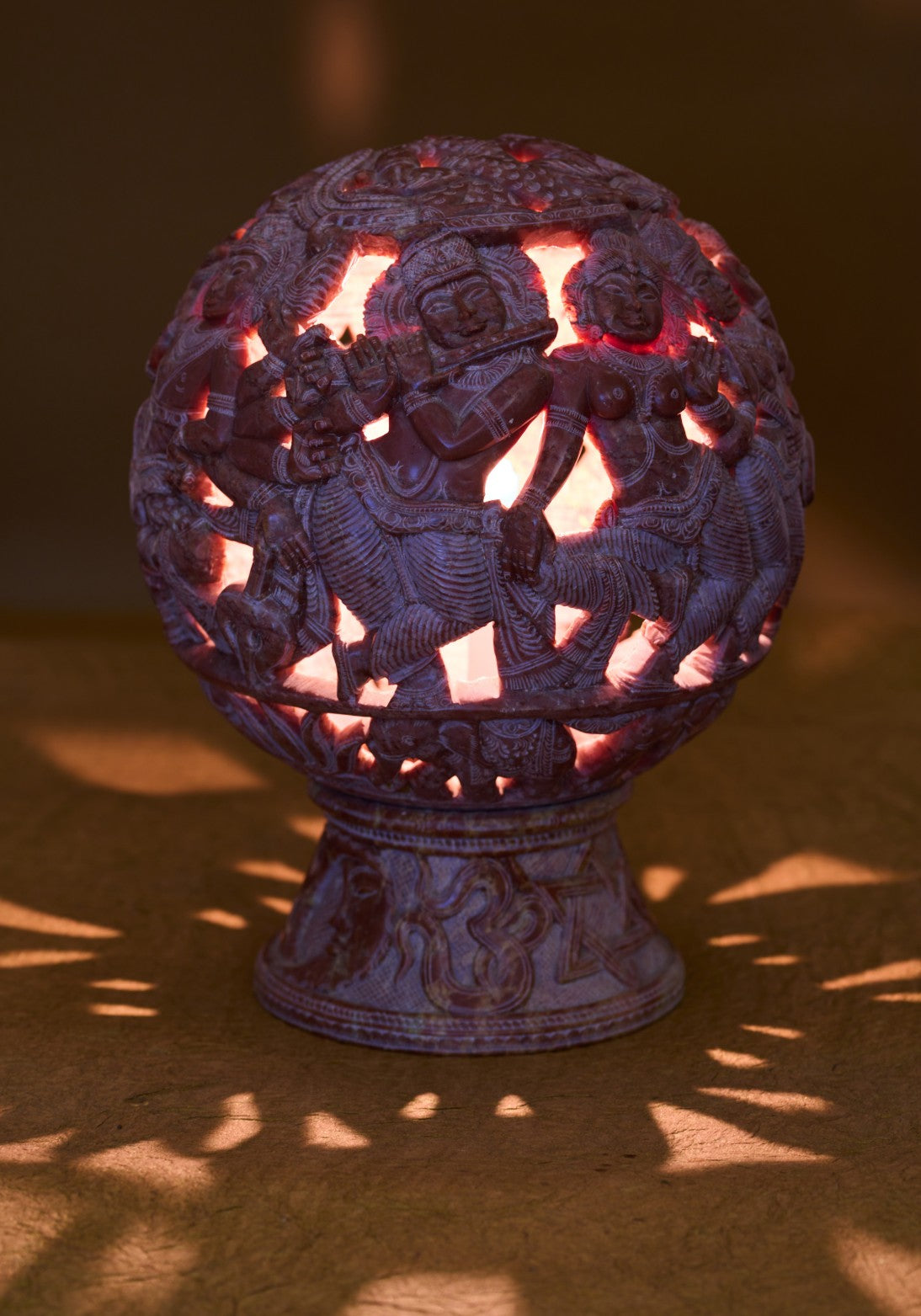 Glowing red stone lamp shade with cutout carvings – spiritual home accent.