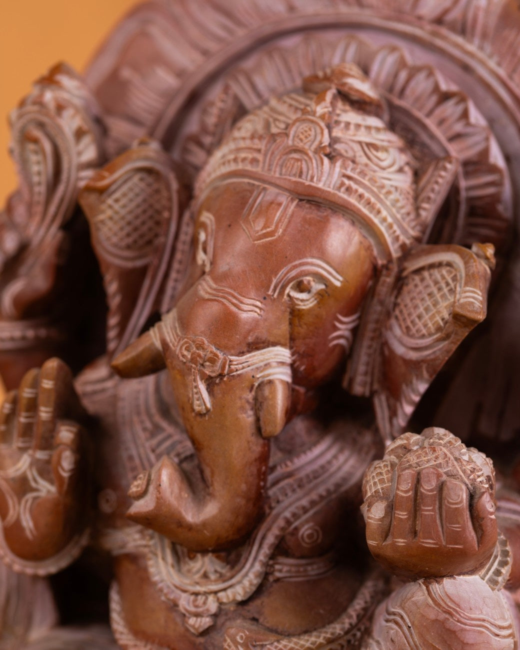 Detailed close‑up of red stone Ganesh sculpture showing carved earrings and trunk