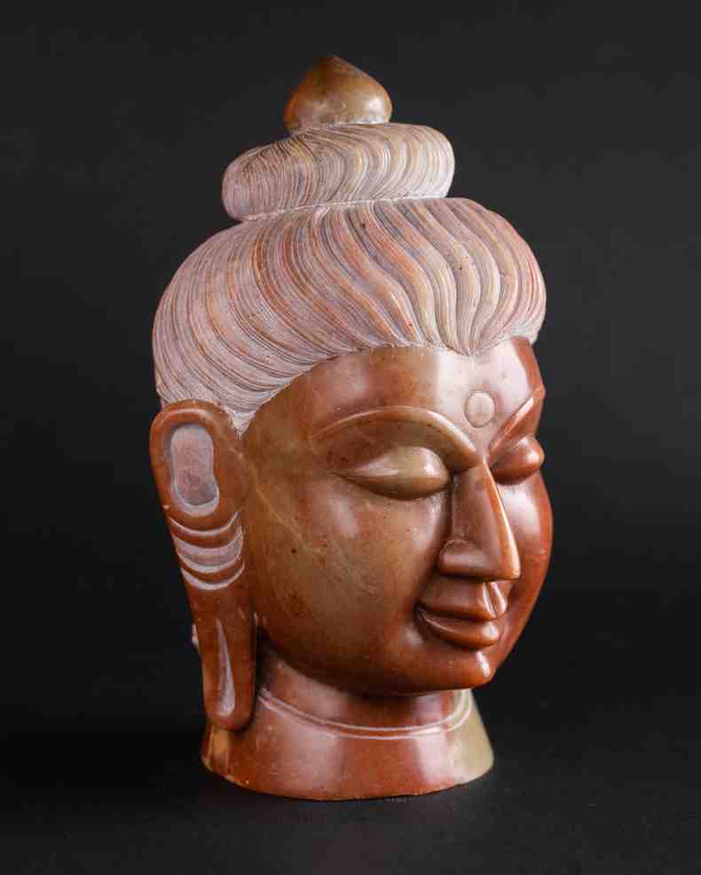 Red stone Buddha head statue front view carved from terracotta-hued marble