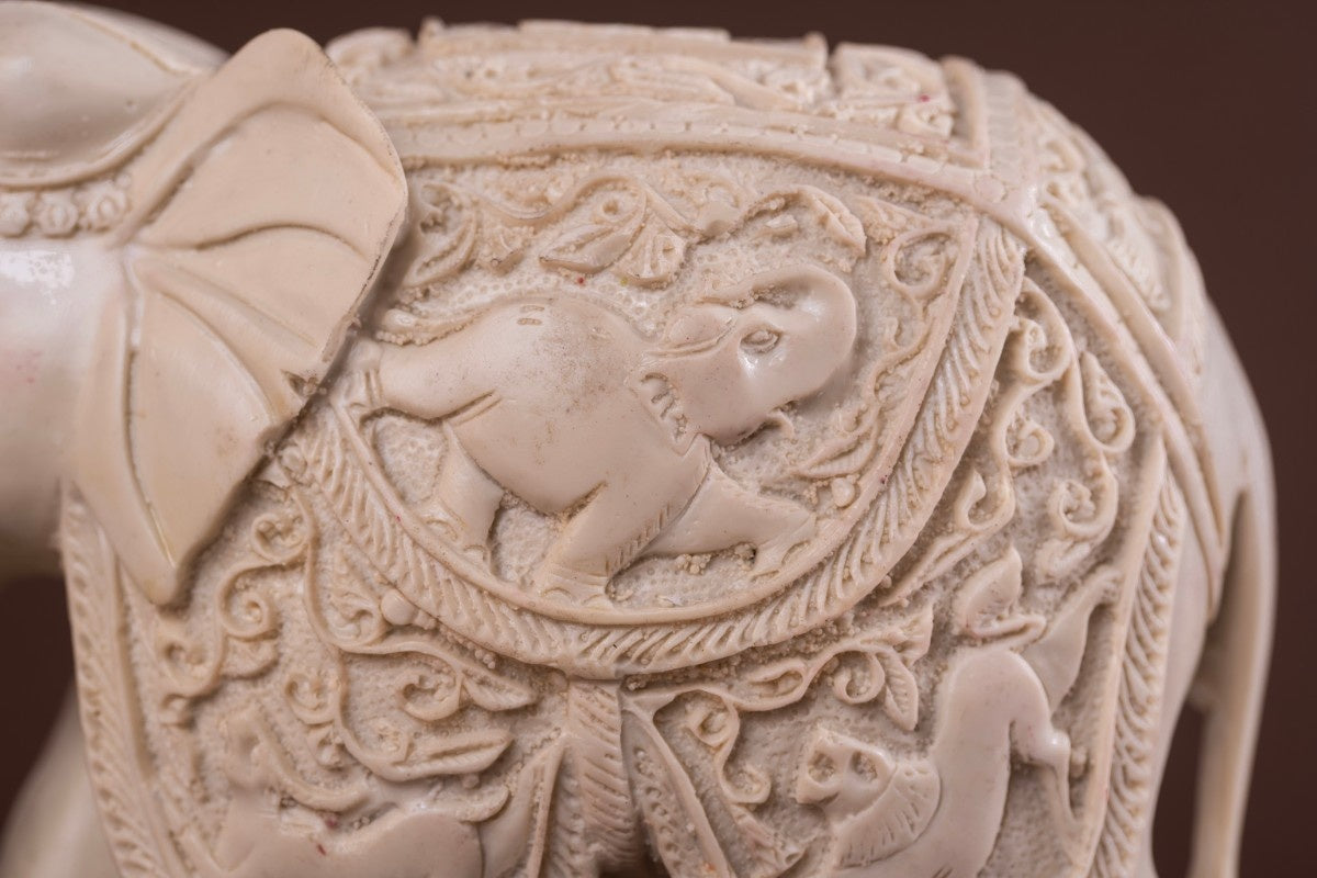 White elephant statue close-up carved elephant figurine with miniature elephant motif and detailed Indian etching.