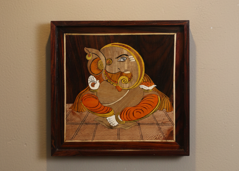 Full view of a Mysore rosewood inlay artwork depicting Lord Ganesha, handcrafted using traditional inlay techniques with contrasting natural woods, set within a polished wooden frame against a warm neutral background.