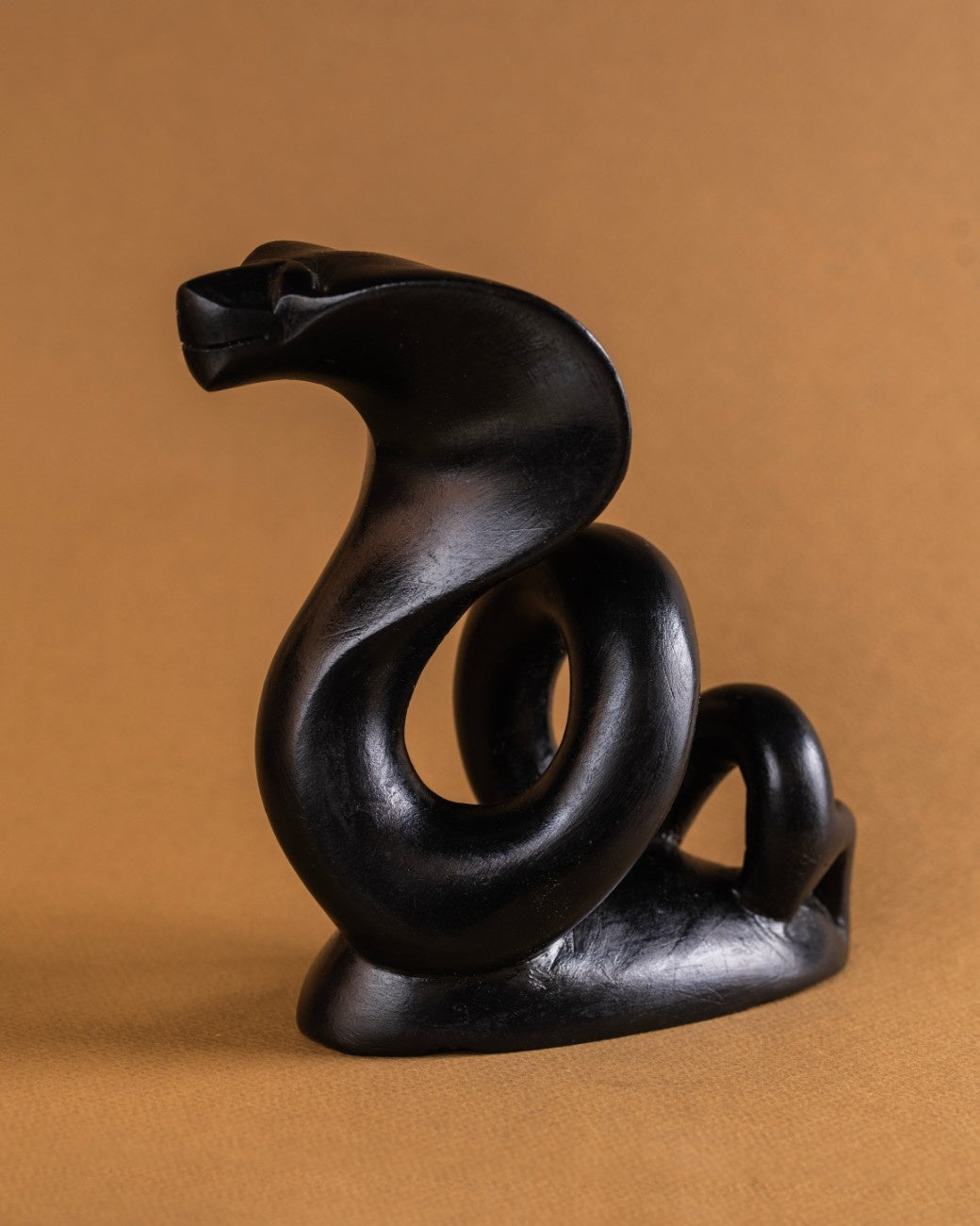 Close-up detail of black stone cobra statue showing polished surface and carving precision