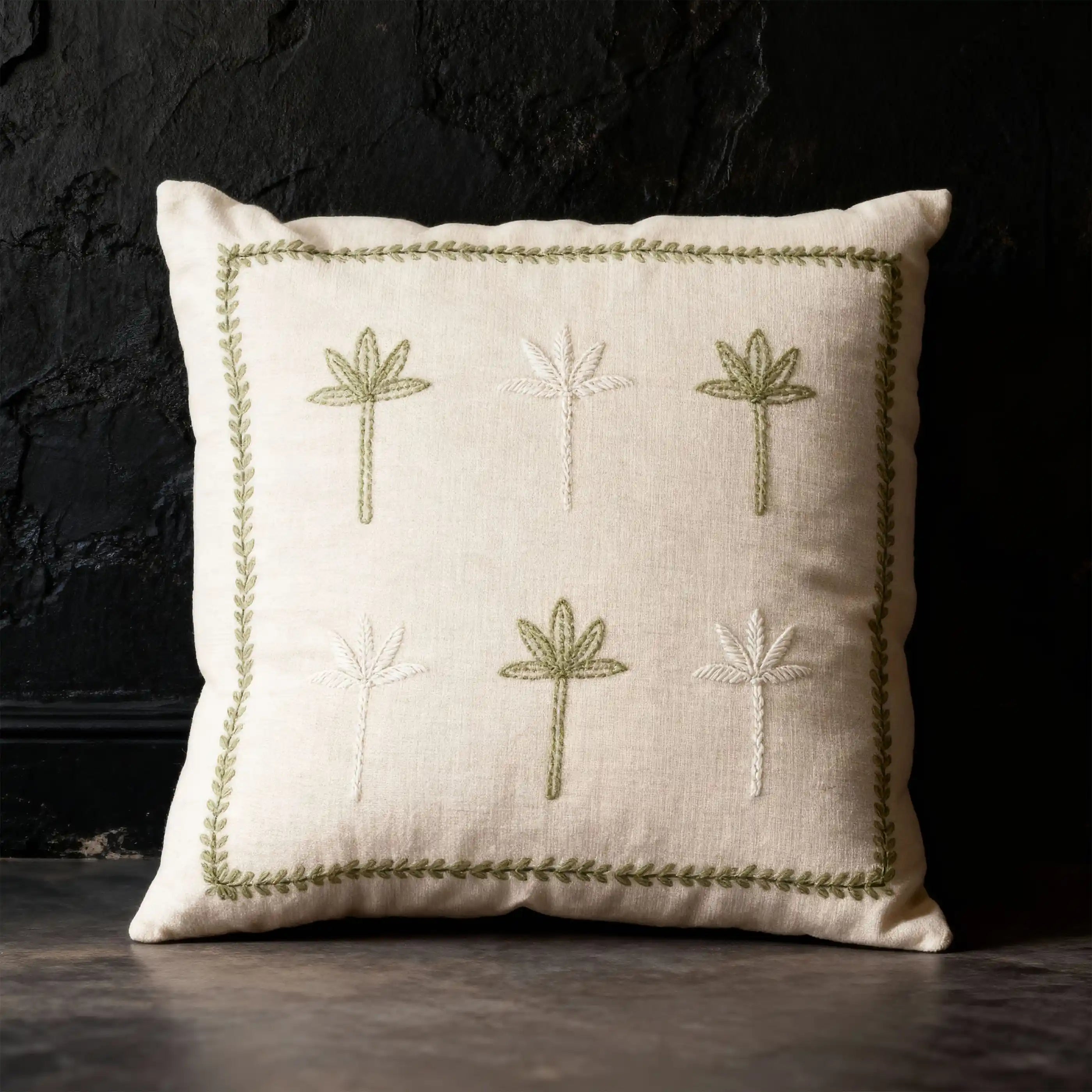 The Botanical Stitch cushion styled against a dramatic black textured wall, highlighting how the cream fabric catches the light.