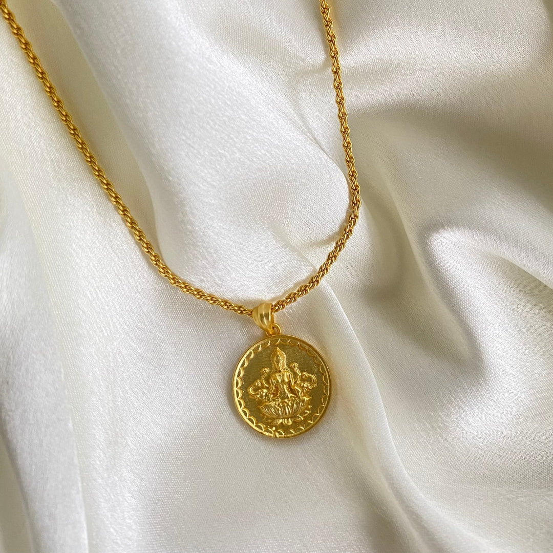 gold plated devi lakshmi coin pendant necklace on white satin fabric
