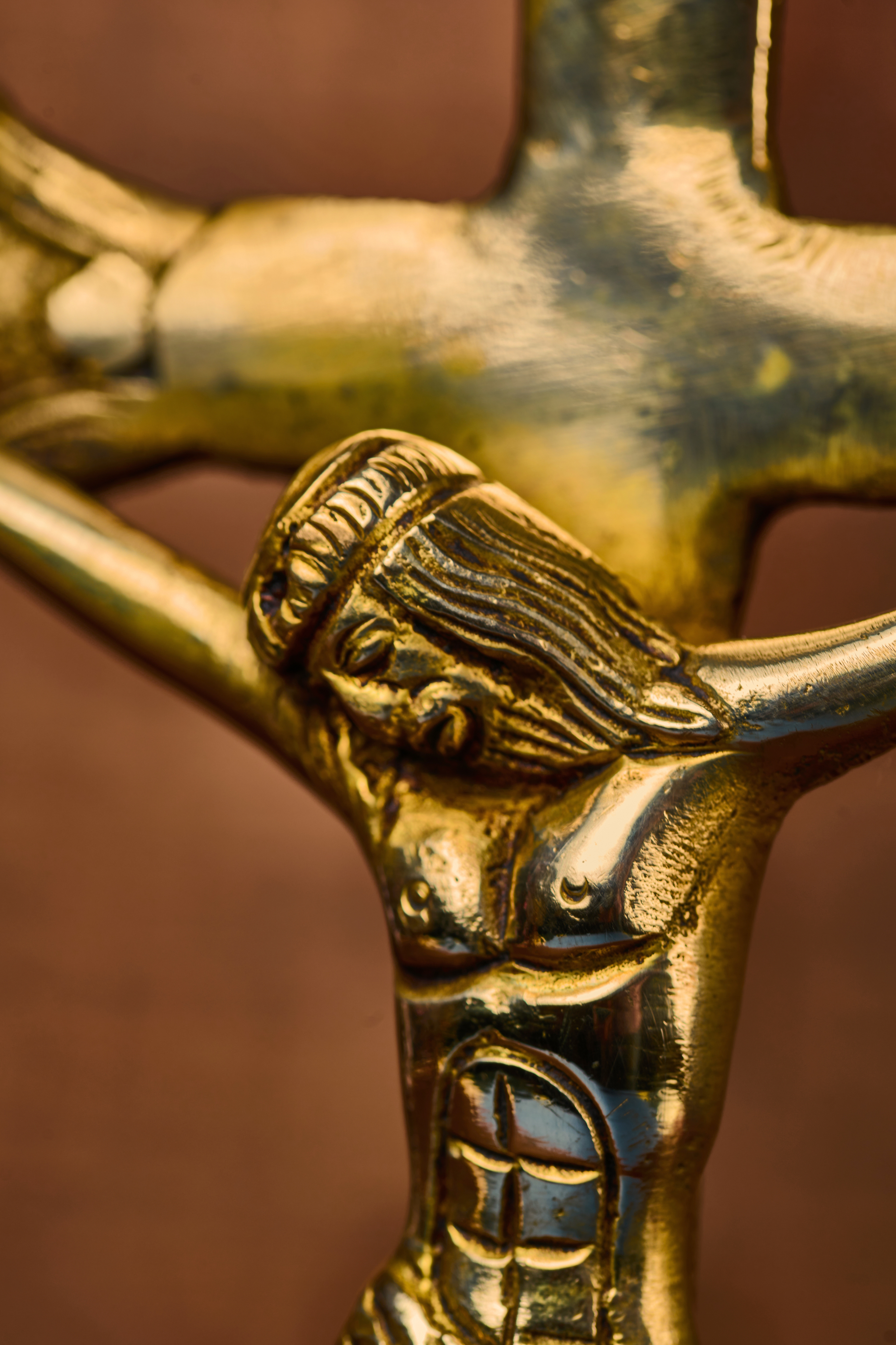 Detailed close-up of solid brass Christ figure on cross highlighting etched metalwork and artisan craftsmanship.