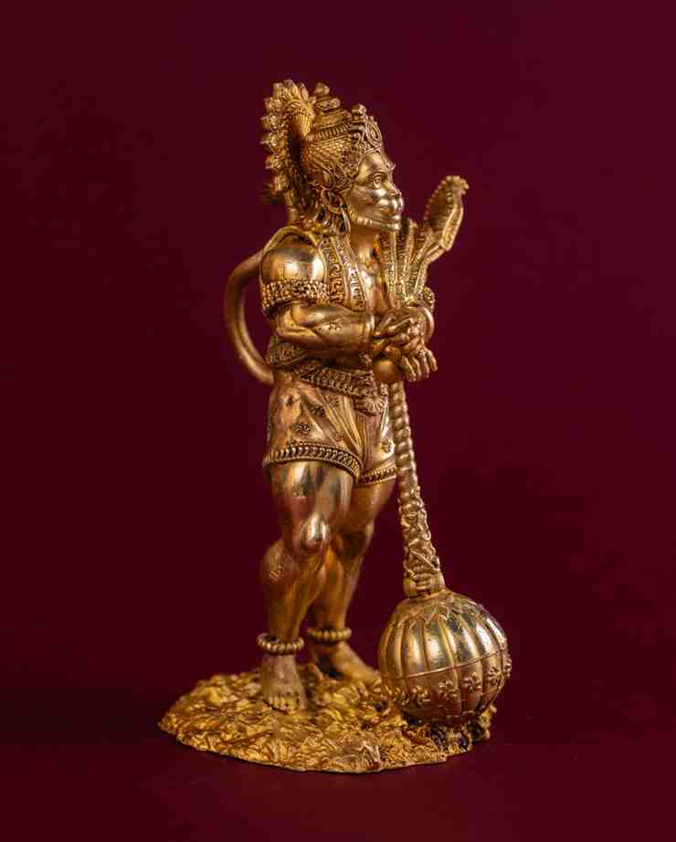Angled view of brass Hanuman idol with gada and ornate armor detailing, handcrafted Indian spiritual décor.